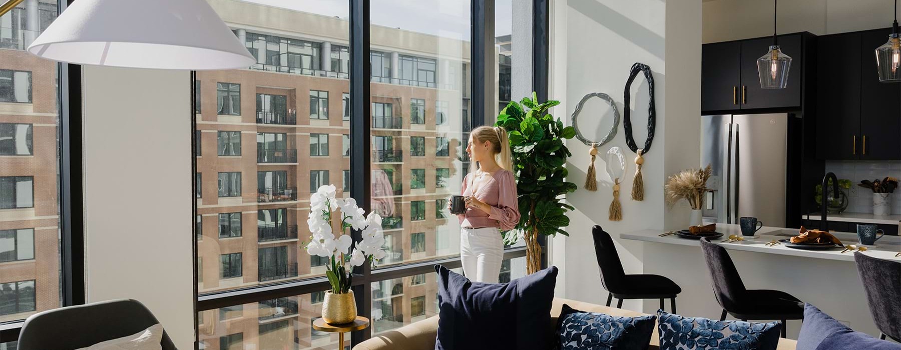 Woman standing in the living room at Overlook at Radius Dilworth apartment looking out the large floor to ceiling windows.